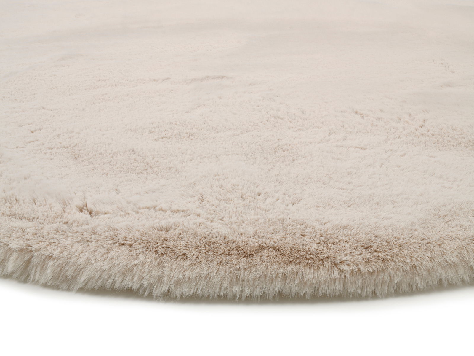 Nahaufnahme eines weichen, beigen Fellteppichs mit flauschiger Textur.