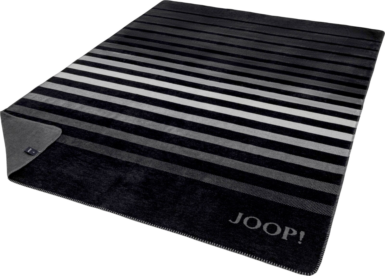 Gestreifte JOOP! Wohndecke in Schwarz-, Grau- und Weißtönen mit eingewebtem Logo, schräg von oben in Perspektive fotografiert; eine Ecke ist umgeschlagen und zeigt die Rückseite.