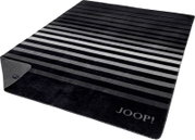 Gestreifte JOOP! Wohndecke in Schwarz-, Grau- und Weißtönen mit eingewebtem Logo, schräg von oben in Perspektive fotografiert; eine Ecke ist umgeschlagen und zeigt die Rückseite.