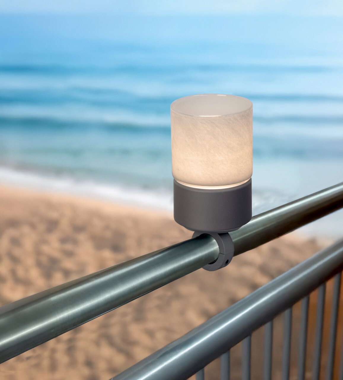 Akku-Windlicht auf einem Geländer mit Blick auf den Strand und das Meer im Hintergrund, seitliche Perspektive.