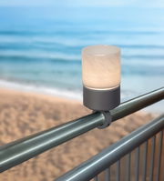 Akku-Windlicht auf einem Geländer mit Blick auf den Strand und das Meer im Hintergrund, seitliche Perspektive.