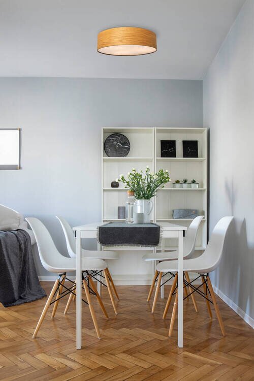 Moderne plafondlamp met houtlook, gemonteerd aan het plafond van een stijlvol ingerichte eetkamer, gezien vanuit de kamer.