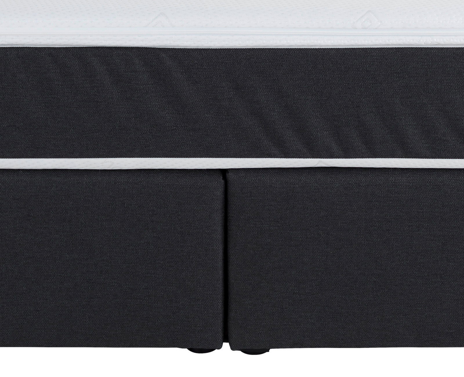 Nahaufnahme eines Boxspringbettes in dunklem Stoff mit weißem Rand, Vorderansicht.