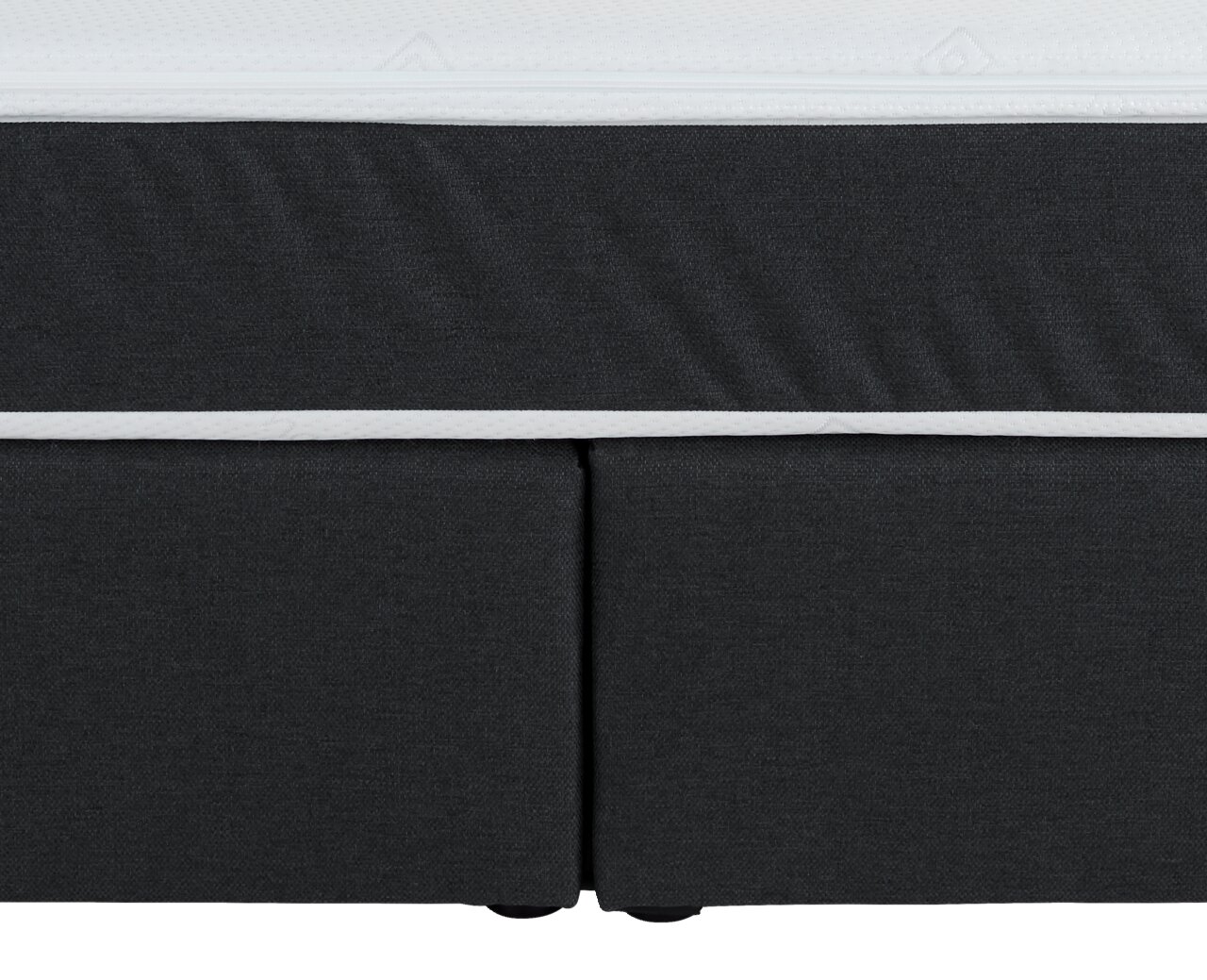 Nahaufnahme eines Boxspringbettes in dunklem Stoff mit weißem Rand, Vorderansicht.