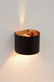 Moderne Wandleuchte XIO in Schwarz mit goldener Innenseite, die warmes Licht nach oben und unten abstrahlt. Seitliche Perspektive.