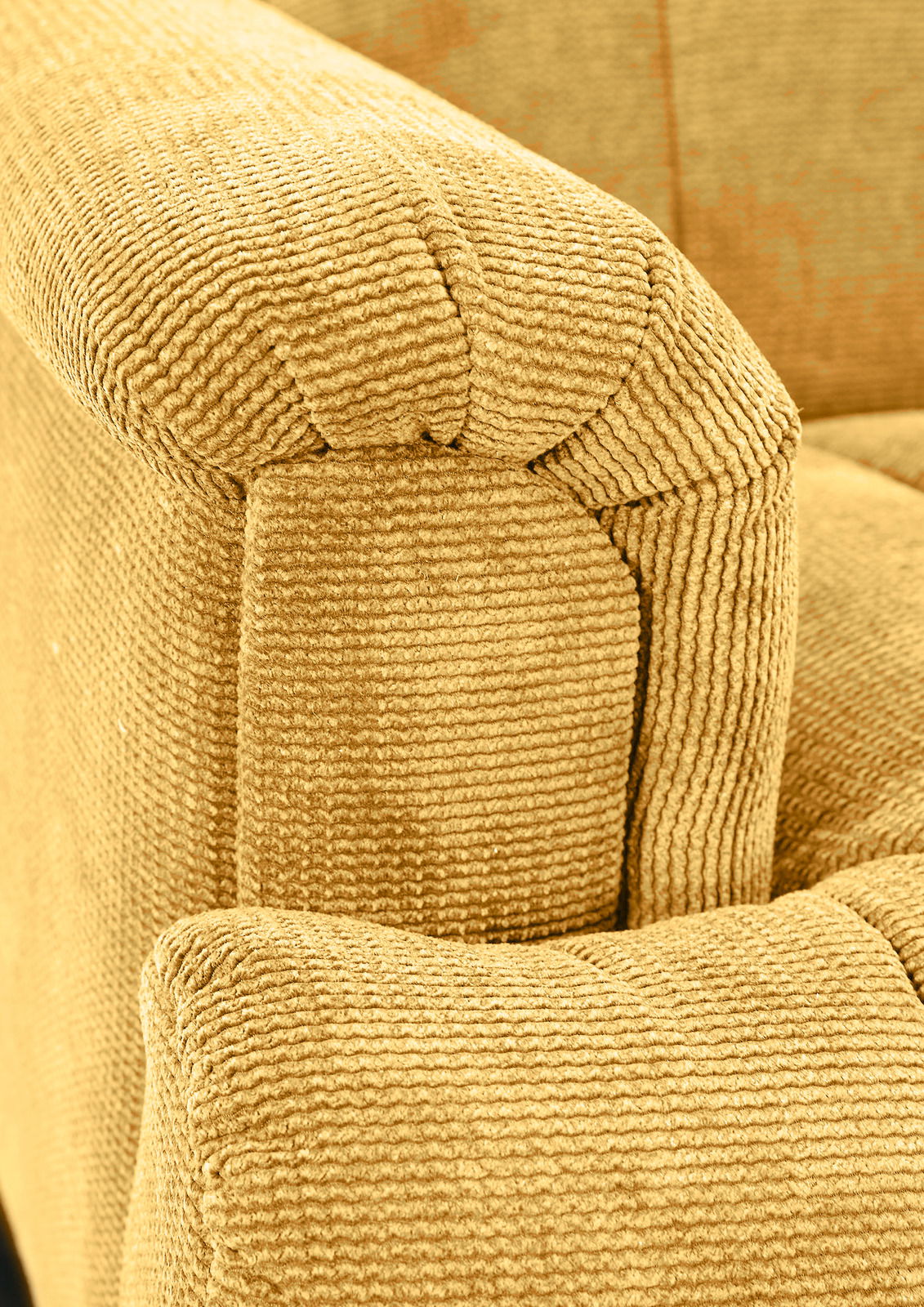 Nahaufnahme einer gelben, strukturierten Polsterecke eines Sofas aus der Perspektive von oben.