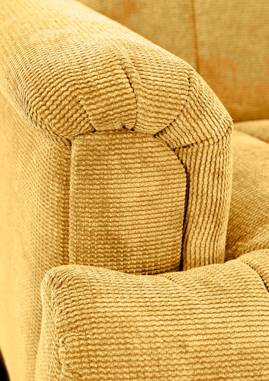 Nahaufnahme einer gelben, strukturierten Polsterecke eines Sofas aus der Perspektive von oben.
