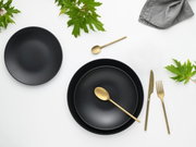Zwart servies Soft Touch, 12-delig, met goudkleurig bestek, gefotografeerd vanuit vogelperspectief, versierd met groene bladeren.