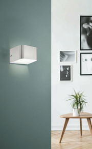 Moderne Wand- und Deckenleuchte SANIA 4 in gebürstetem Metall, seitliche Perspektive, montiert an einer grünen Wand in einem stilvoll eingerichteten Raum.