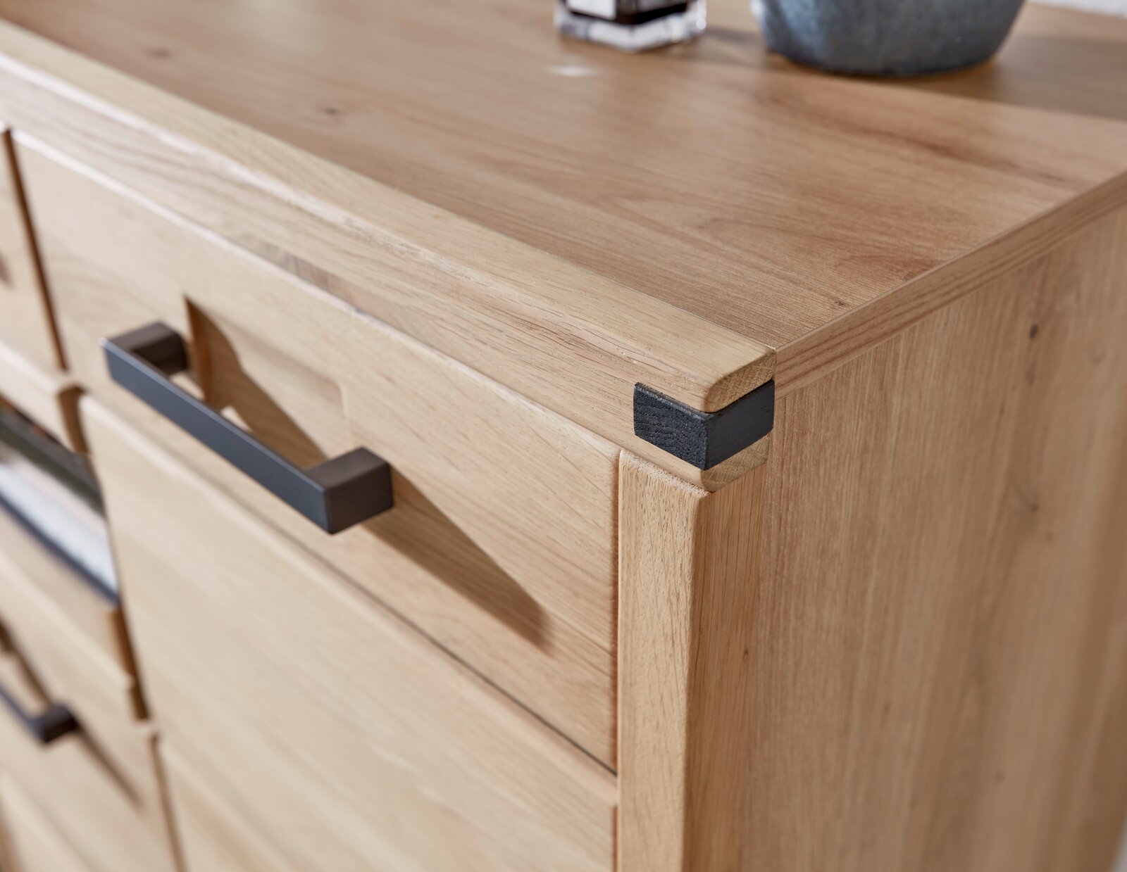 Nahaufnahme eines modernen Schuhschranks aus Holz mit schwarzen Griffen, Perspektive von oben.