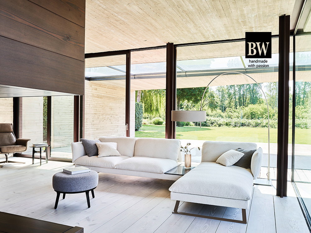 Elegantes Bielefelder Werkstätte-Wohnzimmer mit hellen Möbeln, bodentiefen Fenstern und Blick ins Grüne.