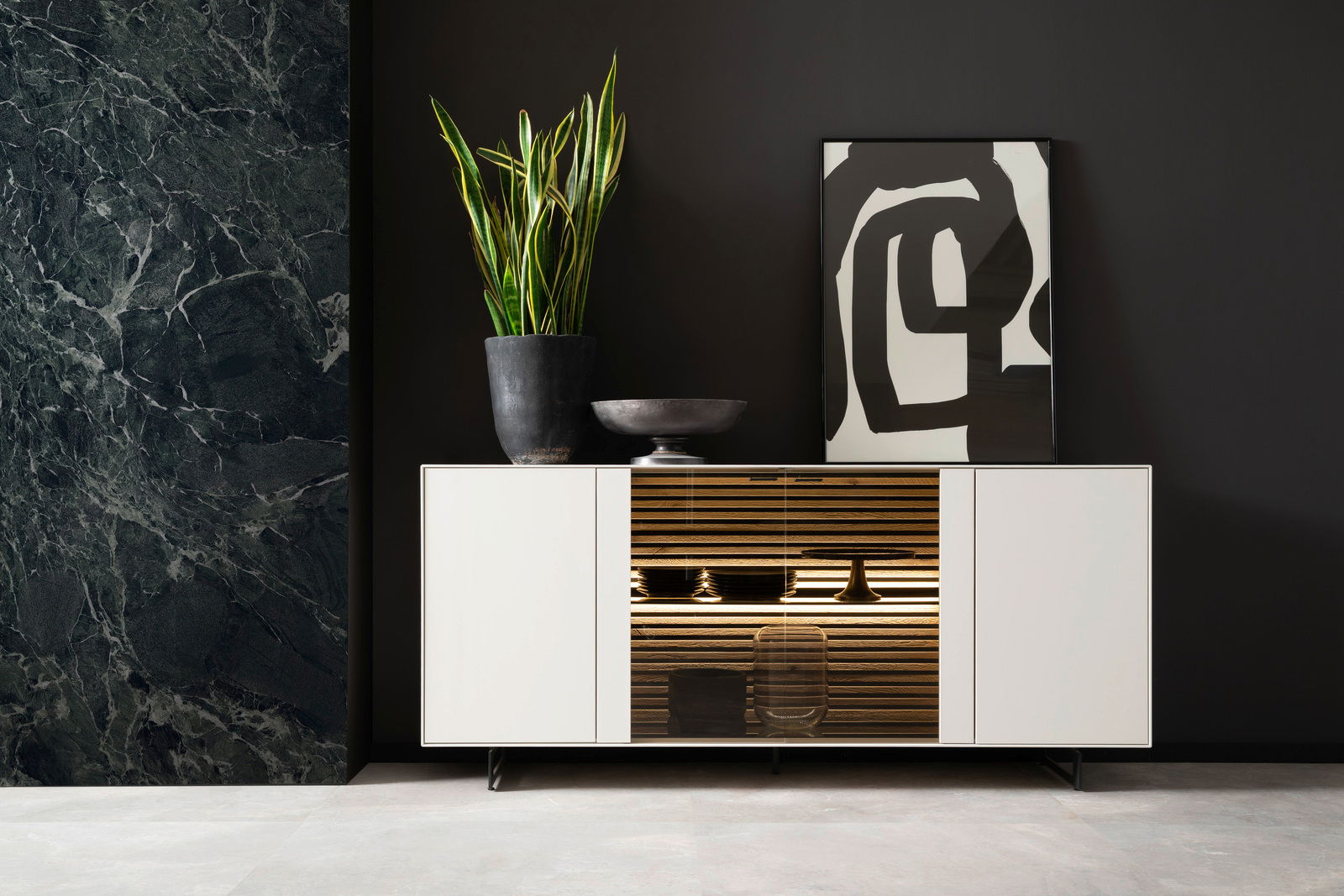 Modernes Sideboard in Weiß mit mittigem Holzregal, dekoriert mit einer Pflanze und Kunstobjekten, frontal betrachtet.