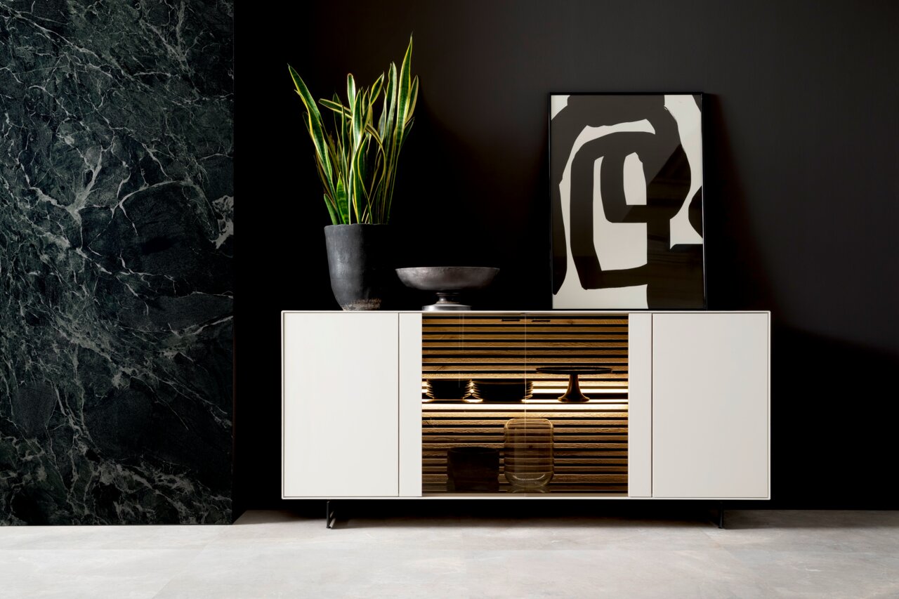 Schöner Wohnen Dressoir YONNA Modernes Sideboard in Weiß mit mittigem Holzregal, dekoriert mit einer Pflanze und Kunstobjekten, frontal betrachtet.