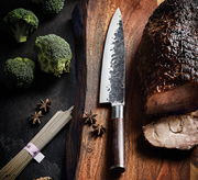 Kochmesser KYOTO 20 cm Wenge auf einem Holzbrett, umgeben von Brokkoli, Sternanis und geschnittenem Fleisch, aus der Vogelperspektive.