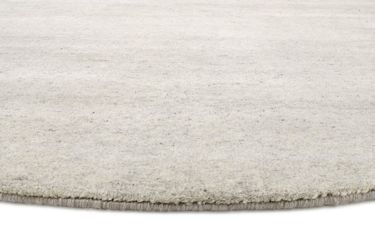 Nahaufnahme eines runden, hellen Wollteppichs mit weicher Textur.
