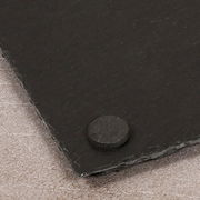 Nahaufnahme einer Schieferplatte mit runder Gummifüße an der Ecke, perspektivisch von oben fotografiert.