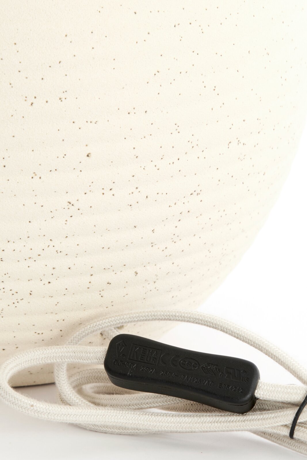 Light&Living Lampvoet ULLOA Close-up van een crèmekleurige lampvoet met fijne spikkels en een witte kabel met een zwarte schakelaar, gezien vanaf de zijkant.