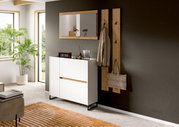 Modernes Flur-Set mit weißer Kommode auf schwarzen Metallfüßen, Holzspiegel und Garderobenpaneelen mit Haken an dunkler Wand, Ansicht schräg von vorne.