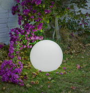 LED-Kugelleuchte Buly 20 kabel im Garten, umgeben von lila Blumen, seitliche Perspektive