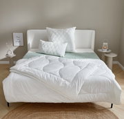 Het gezellige winterbed TENDRE in een stijlvolle slaapkamer, van voren gefotografeerd, met een wit dekbed en bijpassende kussens op een modern bed.