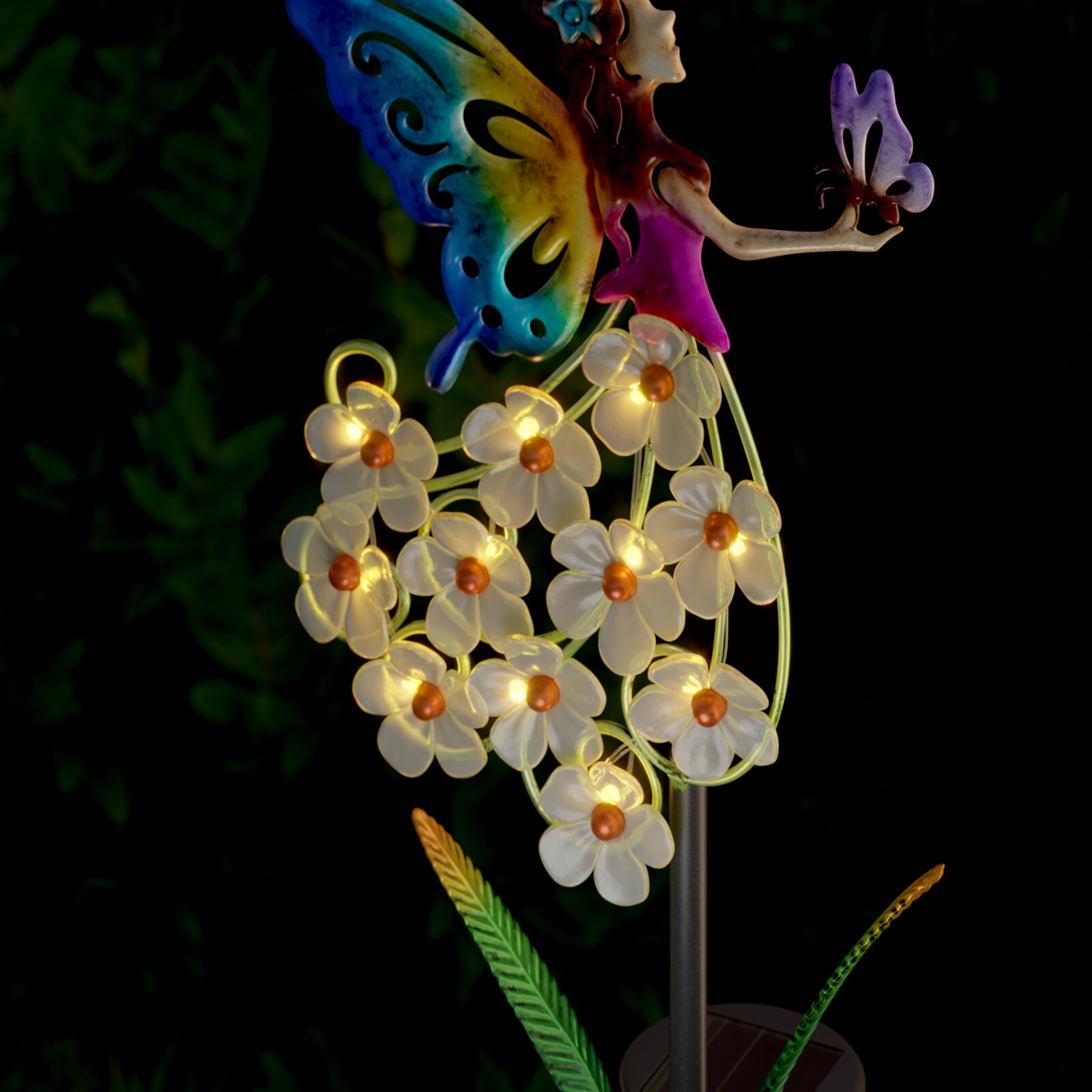 Close-up vanuit zijaanzicht: decoratieve tuinlamp op zonne-energie met een kleurrijk elfje en stralend witte bloemen tegen een donkere achtergrond