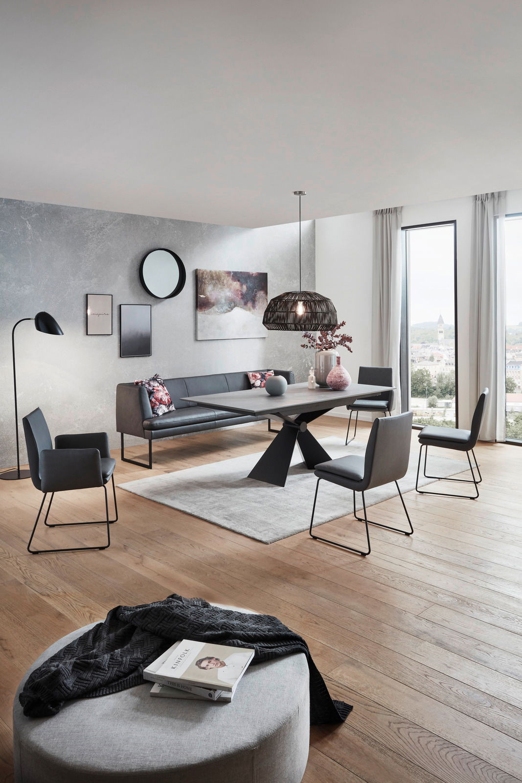 Moderner Esstisch mit schwarzem Metallgestell und dunkler Tischplatte, umgeben von stilvollen Stühlen in einem eleganten Esszimmer mit Blick aus der Fensterperspektive.