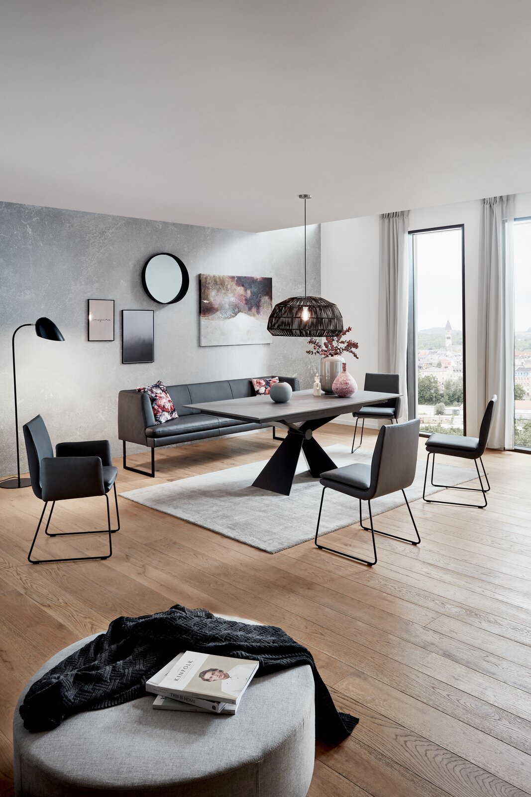 Moderner Esstisch mit schwarzem Metallgestell und dunkler Tischplatte, umgeben von stilvollen Stühlen in einem eleganten Esszimmer mit Blick aus der Fensterperspektive.