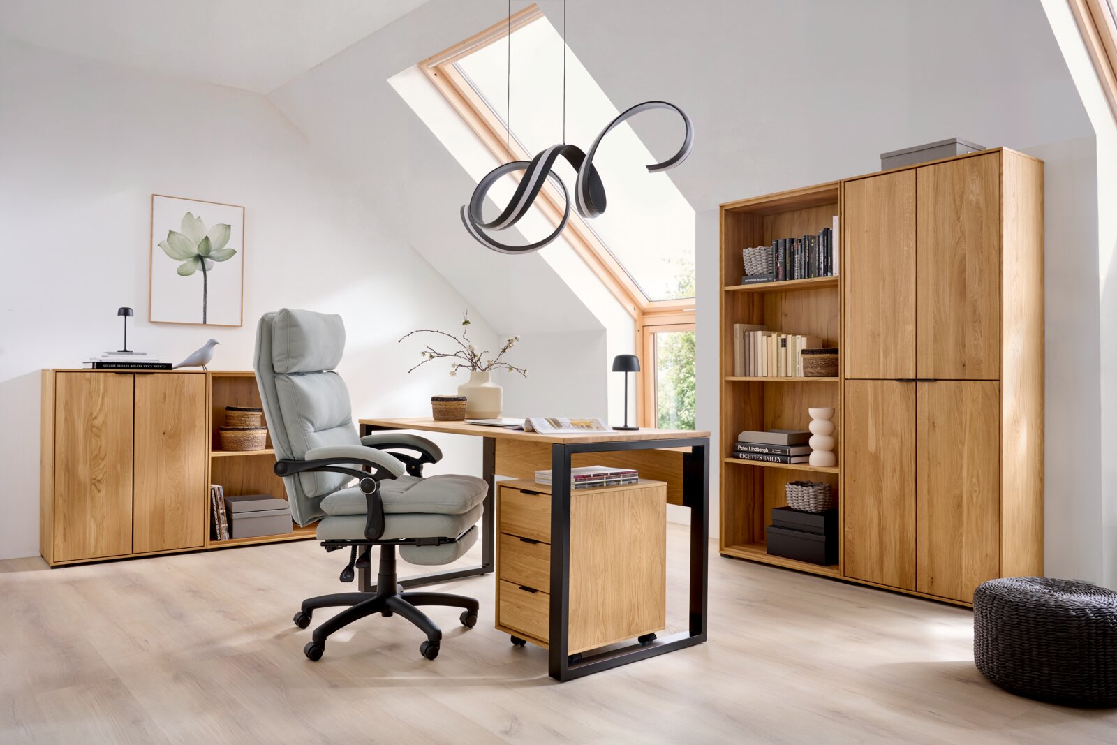 Modernes Homeoffice im Dachgeschoss mit Schreibtisch aus hellem Holz und schwarzem Metallgestell, grauem Bürostuhl, Sideboard und hohem Regal; Ansicht aus leicht erhöhter, frontaler Perspektive.