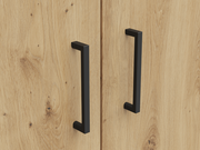 Nahaufnahme von zwei schwarzen Griffen an einer Holztür eines Mehrzweckschranks, aus der Frontalperspektive.