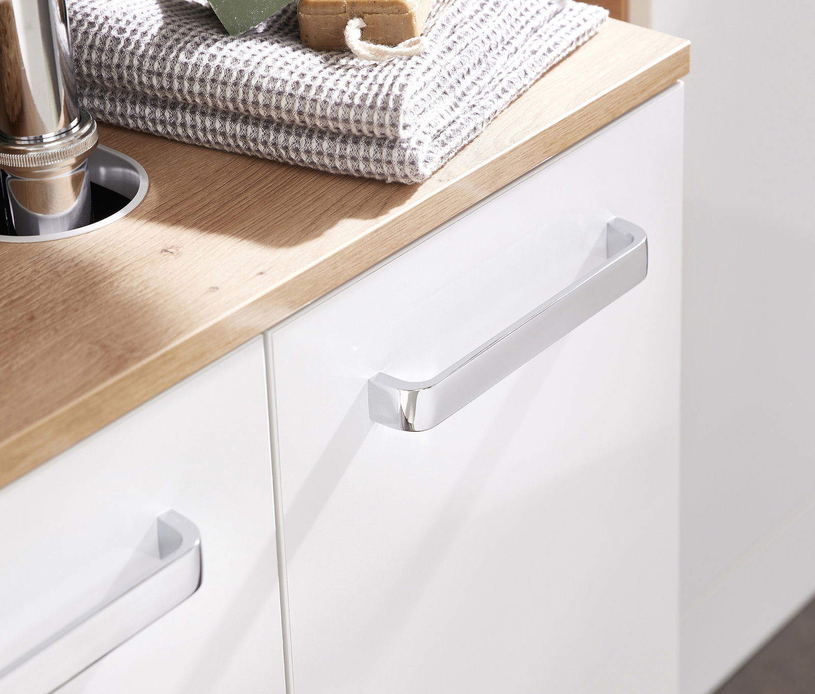 Nahaufnahme eines modernen Waschbeckenunterschranks mit weißer Front und Holzarbeitsplatte, seitliche Perspektive