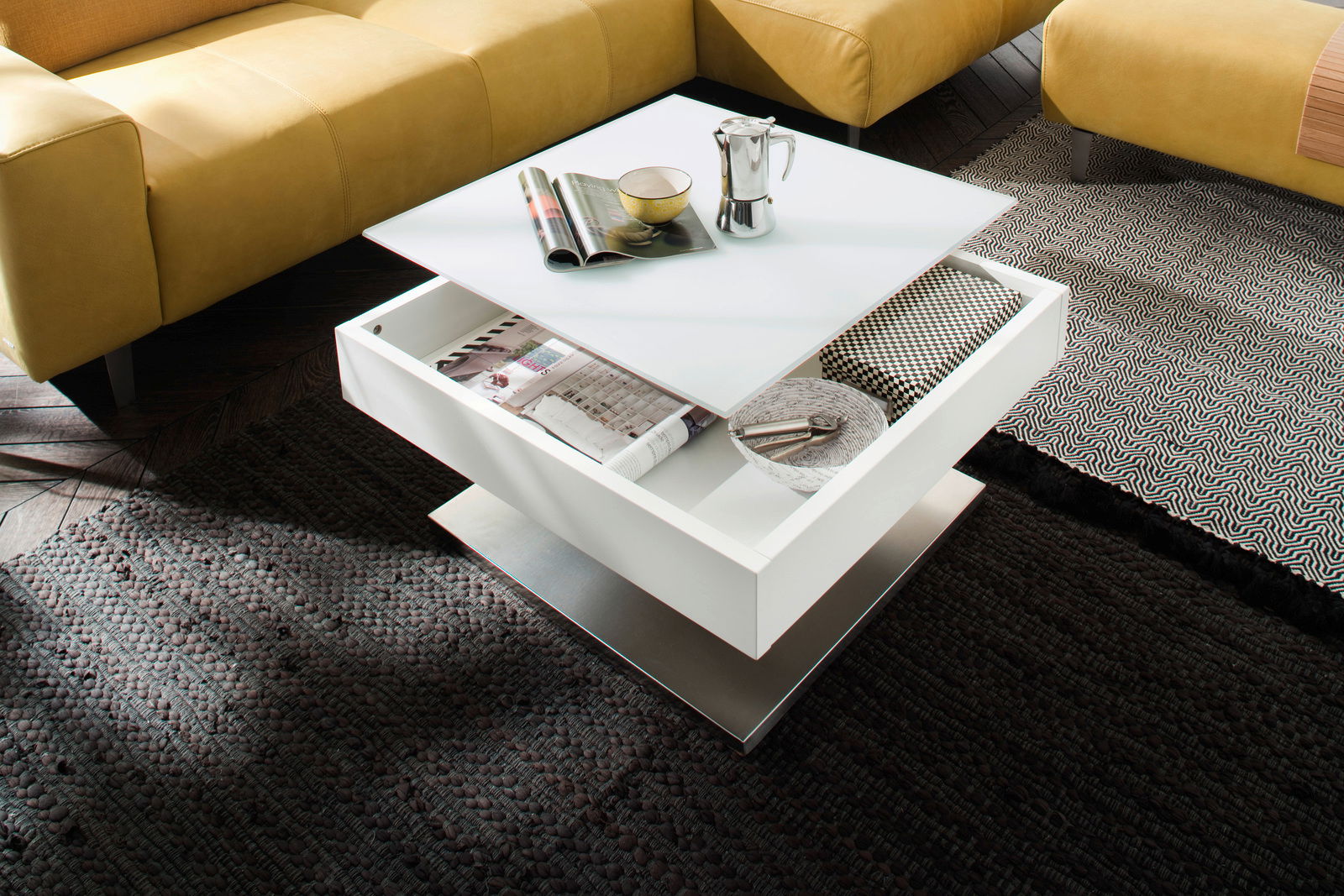 Moderner weißer Couchtisch mit Schublade, von oben fotografiert, umgeben von gelben Sofas und Teppichen.