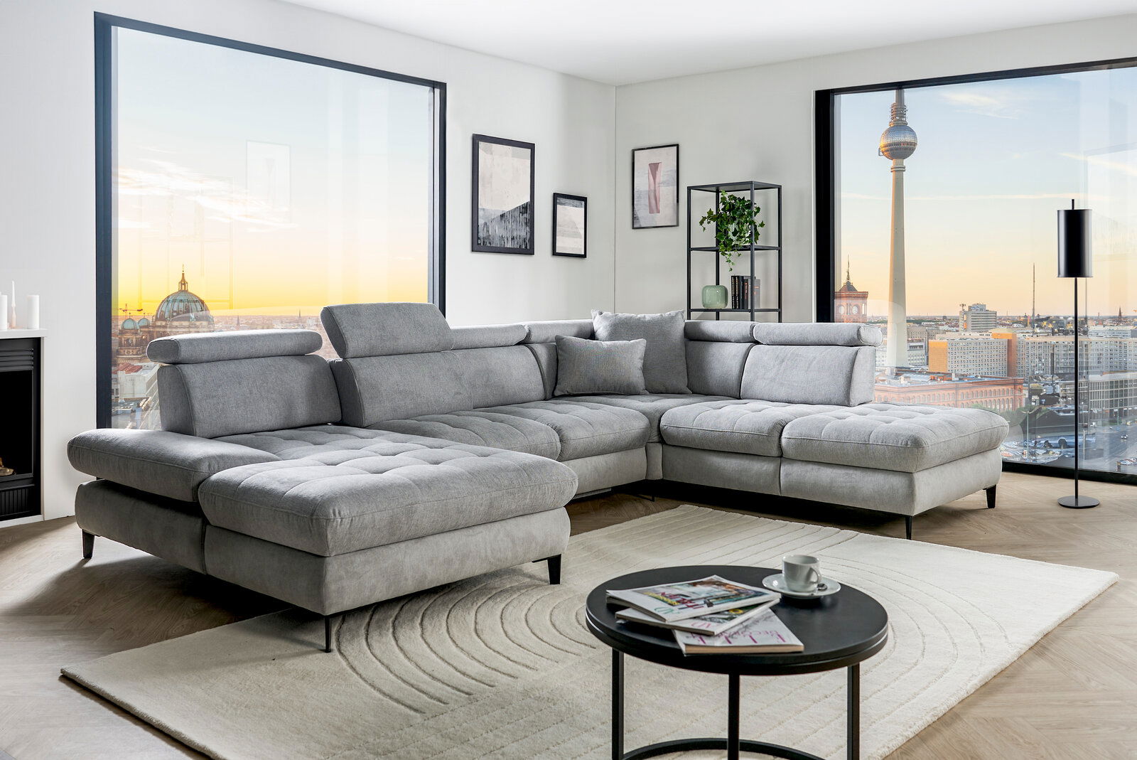 Graue Rundecke (L) in modernem Wohnzimmer mit Blick auf die Stadt, seitliche Perspektive.