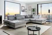 Graue Rundecke (L) in modernem Wohnzimmer mit Blick auf die Stadt, seitliche Perspektive.