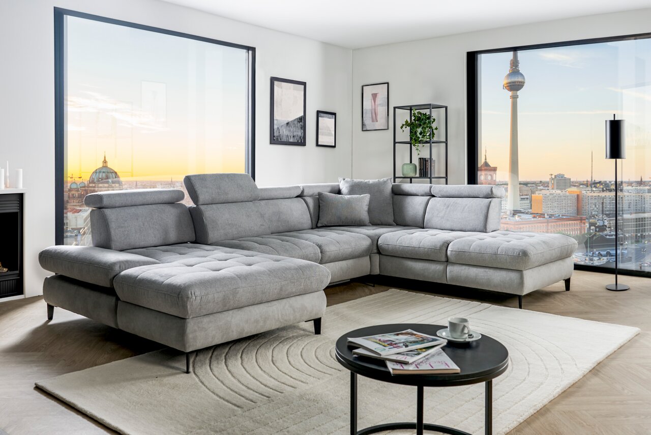 Graue Rundecke (L) in modernem Wohnzimmer mit Blick auf die Stadt, seitliche Perspektive.