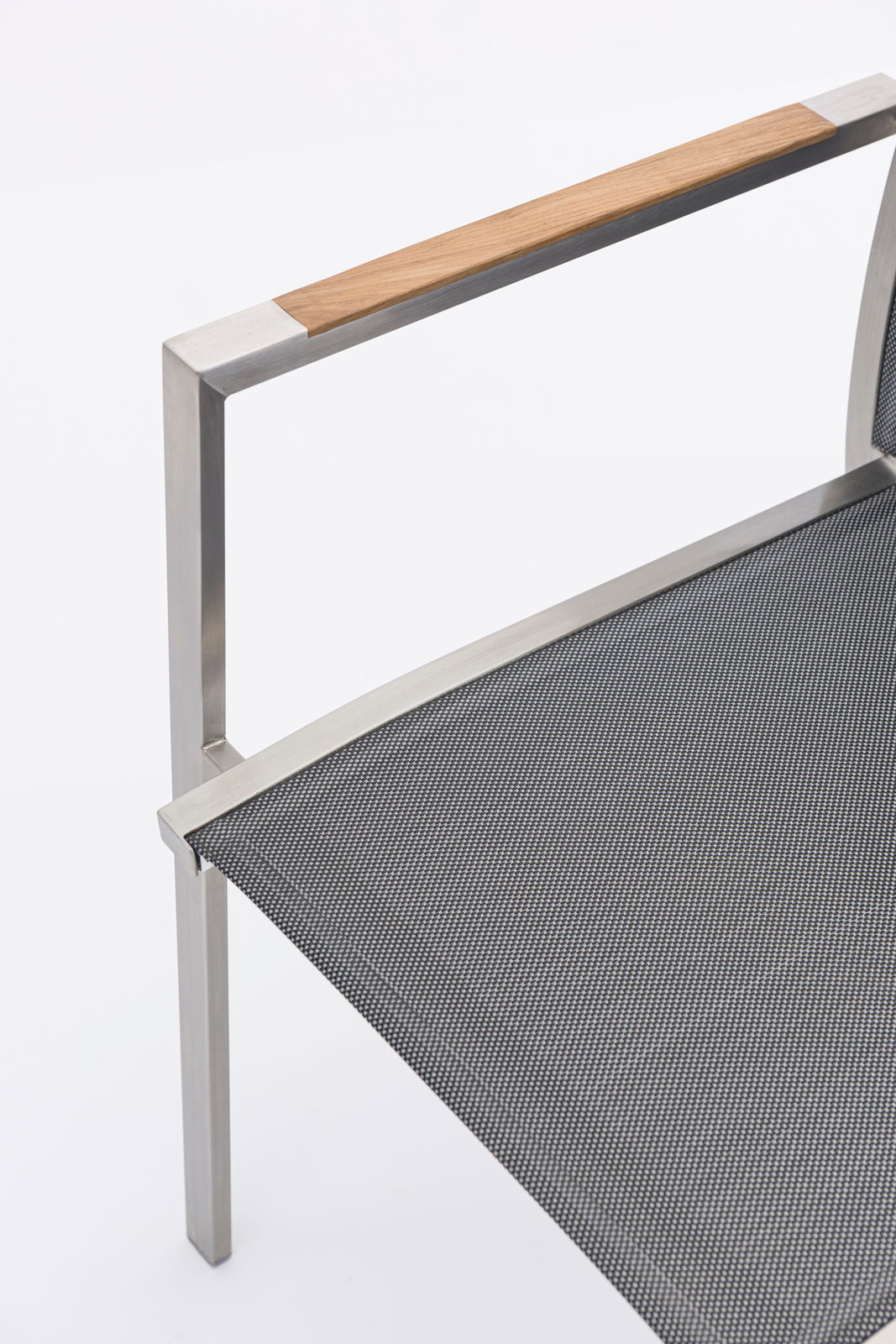 Nahaufnahme eines Stapelsessels mit Metallrahmen und Holzarmlehne, seitliche Perspektive.