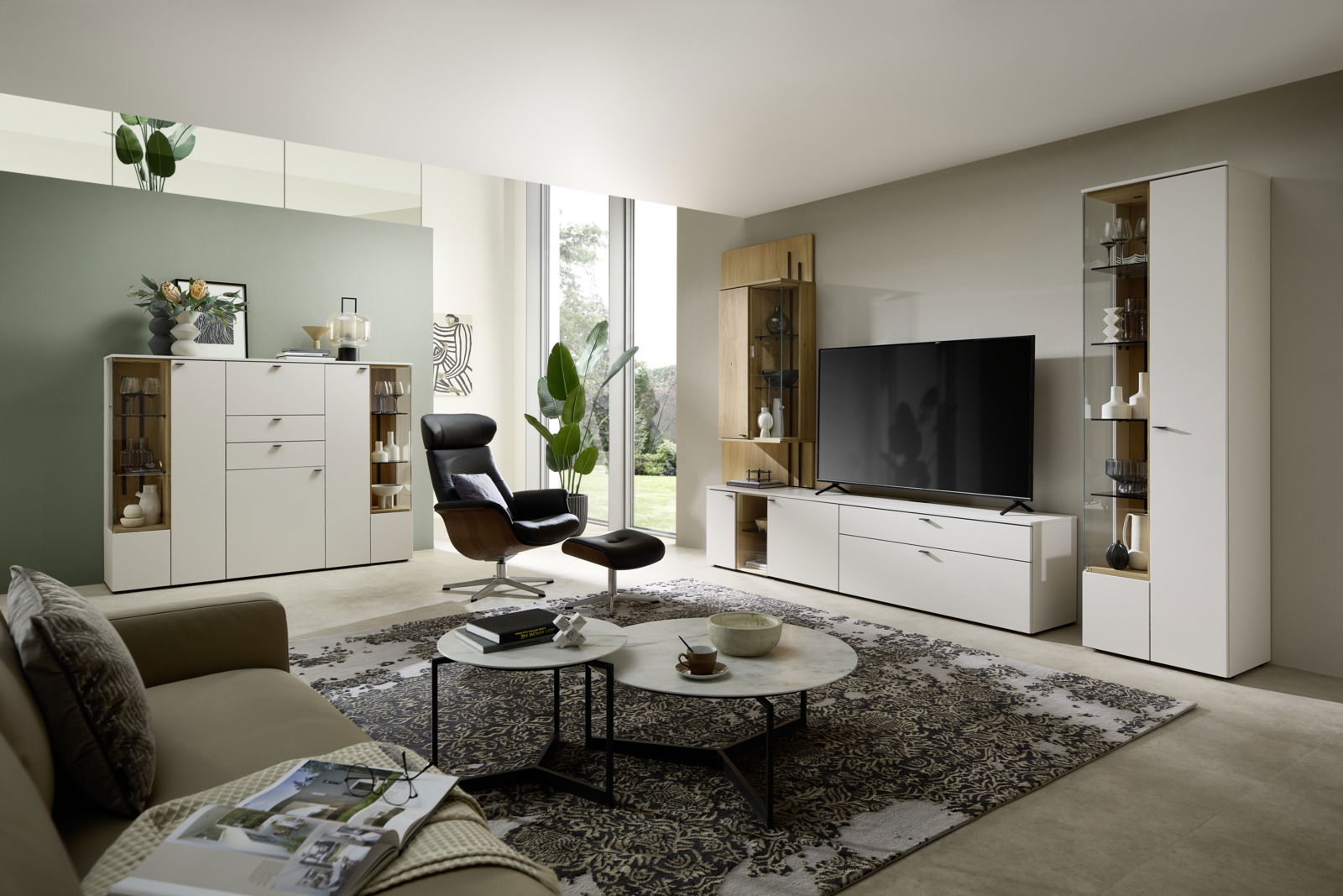 Venjakob Vitrine (R) VANYA Moderne Wohnzimmeransicht mit eleganter weißer Vitrine, die von vorne sichtbar ist, neben einem großen Fernseher und stilvollen Möbeln.