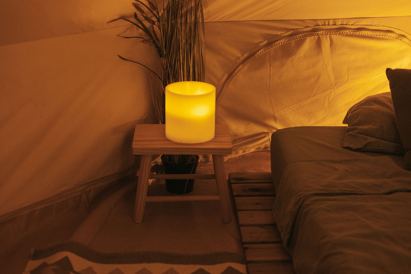 Outdoor-Kerze auf einem Holztisch in einem gemütlichen Zelt, seitliche Perspektive