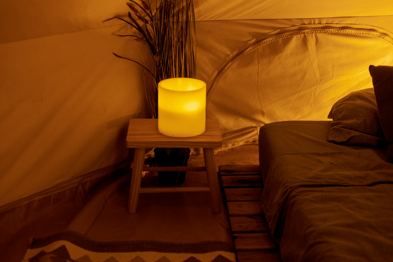 New Garden Outdoor-Kerze DOLO Outdoor-Kerze auf einem Holztisch in einem gemütlichen Zelt, seitliche Perspektive