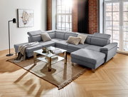 Graue Wohnlandschaft TIM in U-Form mit verstellbaren Kopfstützen, dekoriert mit Kissen und Decke, in einem modernen Wohnzimmer mit großen Fenstern und Holzboden, Perspektive von vorne links.