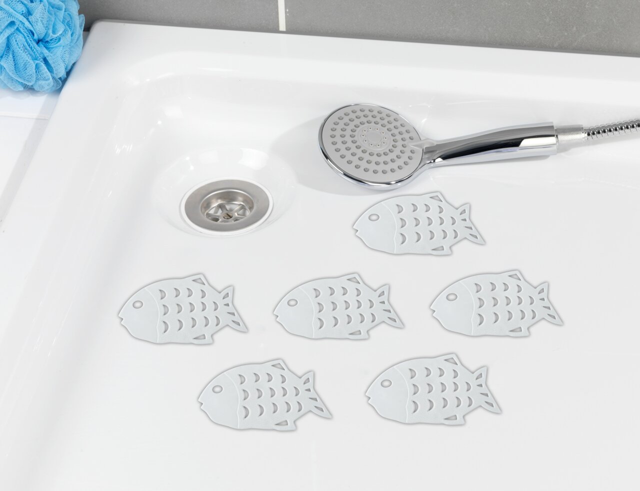 Wenko Stop-Sticker Fish 6-tlg. Sechs rutschfeste Fisch-Sticker in einer Dusche, von oben betrachtet, neben einem Duschkopf.
