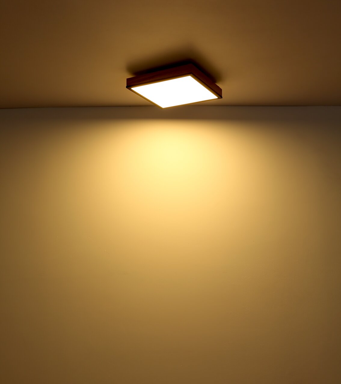 Quadratische Deckenleuchte mit warmem Licht, von unten betrachtet.