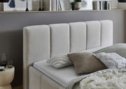 Seitliche Ansicht eines modernen Polsterbetts mit beigem Kopfteil und dekorativen Kissen.