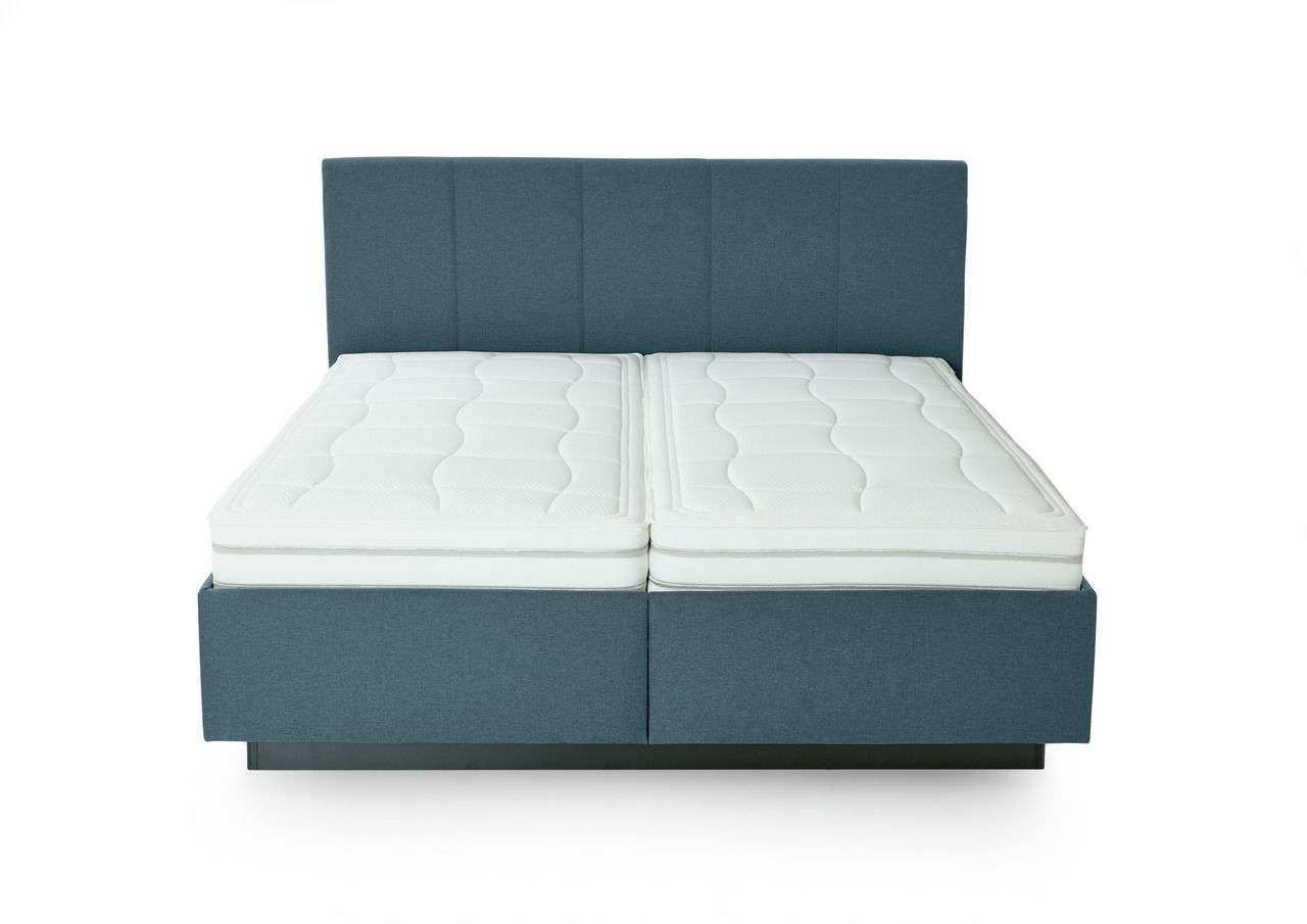Frontale Ansicht eines modernen Polsterbetts mit blauem Stoffbezug und zwei weißen Matratzen.