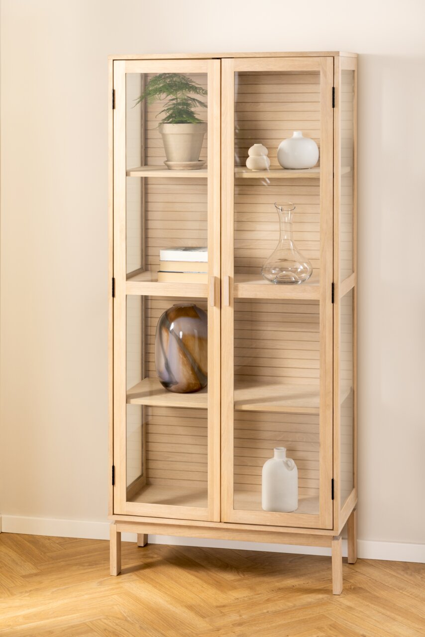Holzvitrine mit Glastüren, frontal fotografiert, mit dekorativen Objekten auf den Regalen.