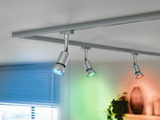 LED-Leuchtmittel in einer modernen Deckenleuchte mit drei Strahlern, die in verschiedenen Farben leuchten. Perspektive von unten.