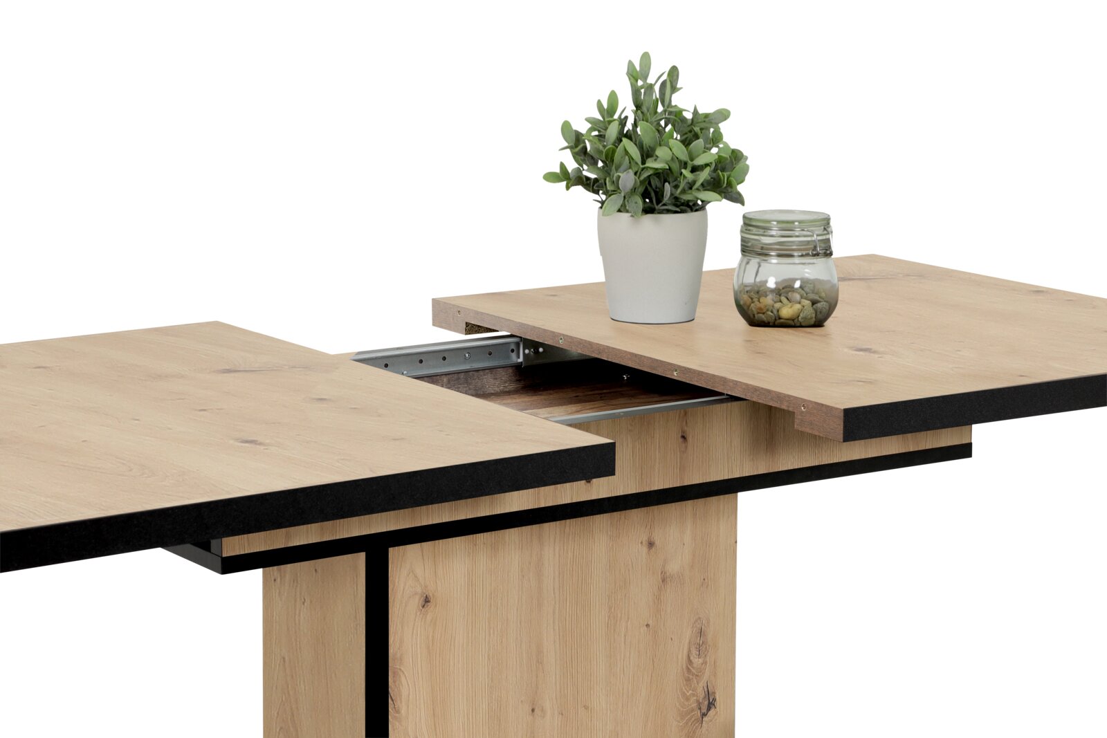 Nahaufnahme eines ausziehbaren Esstisches aus Holz mit schwarzem Rand, dekoriert mit einer Pflanze und einem Glasgefäß, seitliche Perspektive.