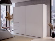 Moderner, weißer Schwebetürenschrank mit zwei Türen, seitliche Perspektive, in einem stilvoll eingerichteten Schlafzimmer mit großen Fenstern und Stadtblick.