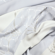 Detailansicht eines Ösenvorhangs mit elegantem Muster in hellen Tönen.