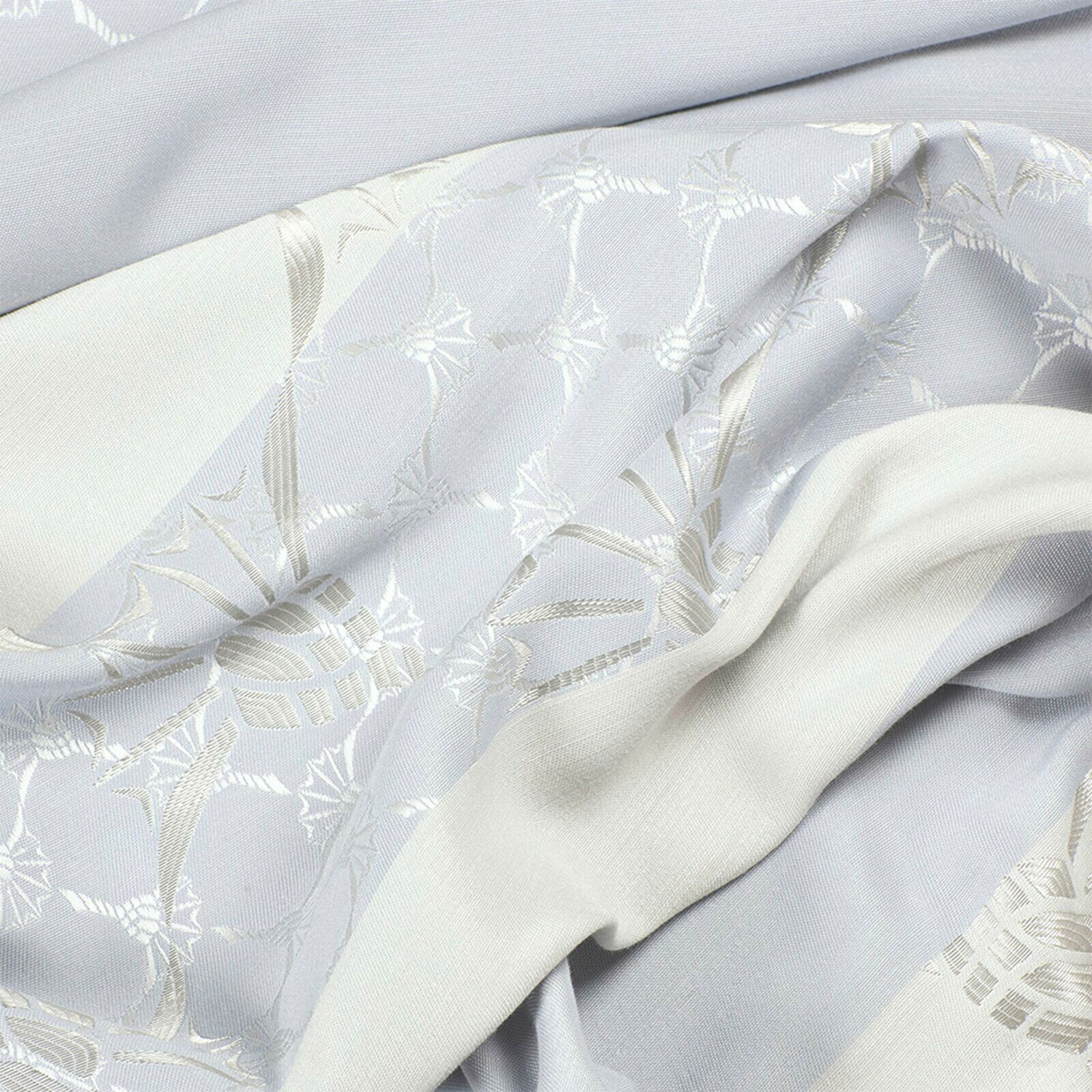 Detailansicht eines Ösenvorhangs mit elegantem Muster in hellen Tönen.