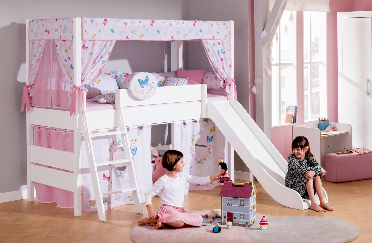 Spielbett mit Rutsche in einem Kinderzimmer, dekoriert mit Schmetterlingsmotiven und rosa Vorhängen, seitliche Perspektive